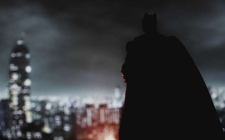 Batman from DC Comics looming over Gotham City at night