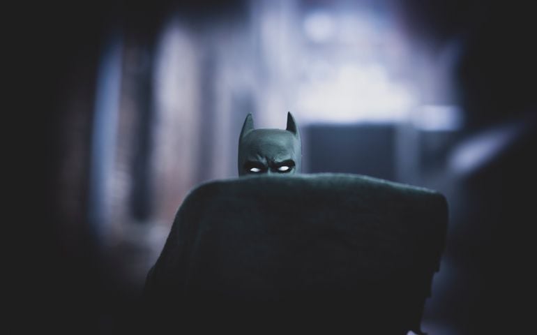 DC Comics Batman obscured by his cape in a back alley