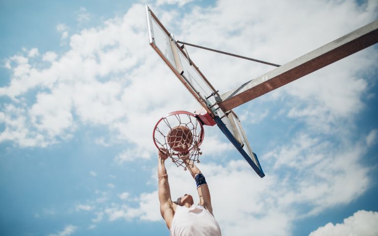 Young male student making a score at the basketball playground