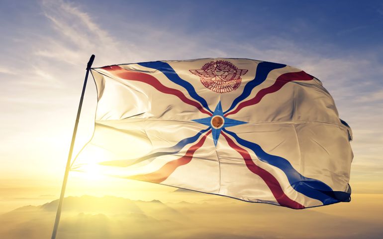 Assyrian people flag on flagpole textile cloth fabric waving on the top sunrise mist fog
