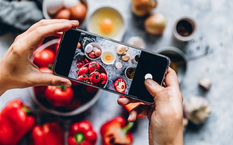 Hands of a woman taking photographs of a ingredients on kitchen counter. Point of view shot.