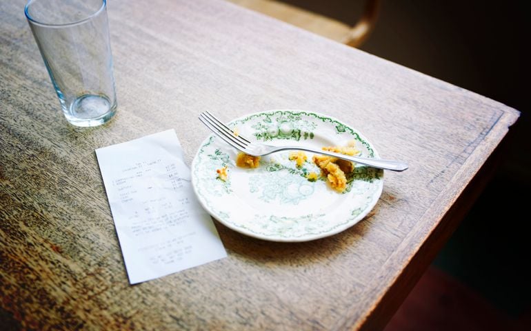 bill and empty plate on table in cafe
