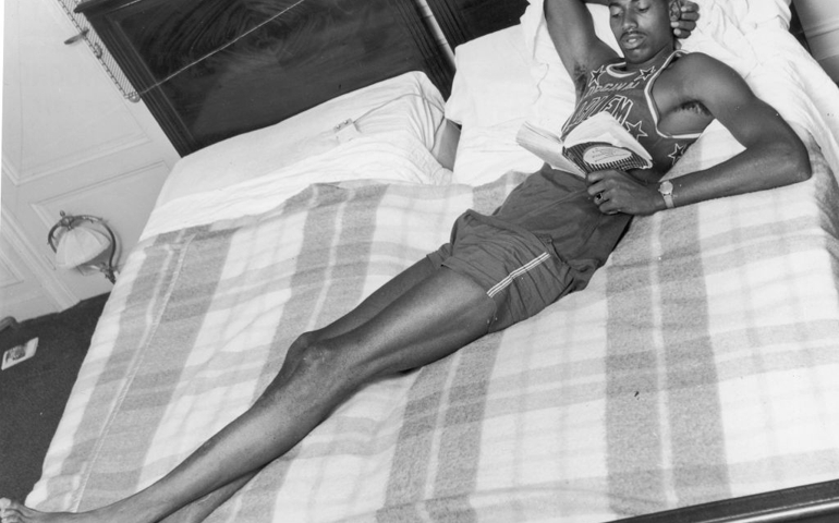 1st September 1958: American basketball player Wilt Chamberlain reads a book while sprawling across two beds in a hotel room, while on tour with the Harlem Globetrotters. The book is 'A Layman's Guide to Psychiatry and Psychoanalysis'.