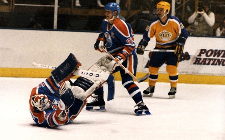 INGLEWOOD, CA - 1985: Goalie Grant Fuhr #31 of the Edmonton Oilers tries to make the save as his teammate Wayne Gretzky #99 skates by with Marcel Dionne #16 of the Los Angeles Kings follows behing circa 1985 at the Forum in Inglewood, California.
