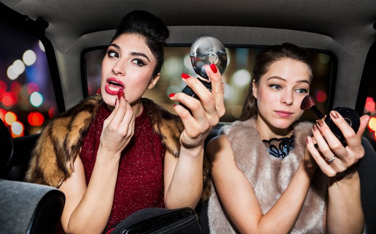 Women touching up make up in car at night time.