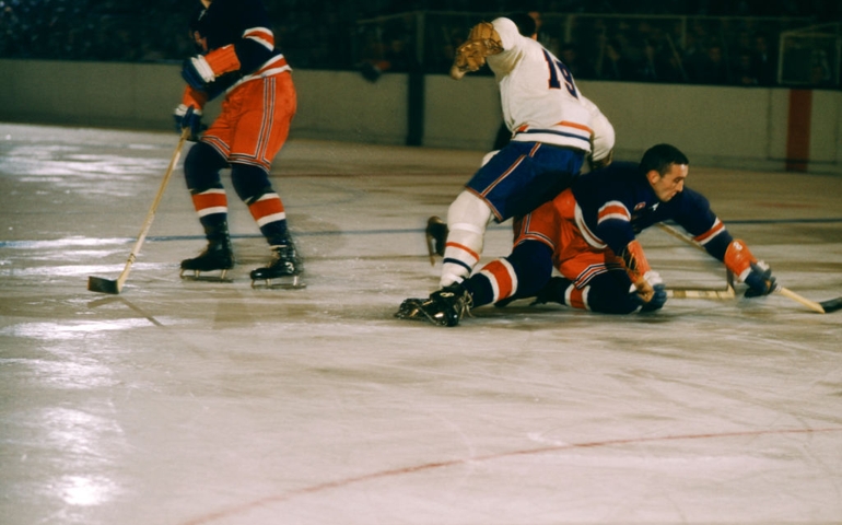 Lou Fontinato #8 of the New York Rangers goes for the puck as he is defended by Dollard St. Laurent #19 of the Montreal Canadiens while Harry Howell #3 of the Rangers follows the play during their game on October 27, 1957 at the Madison Square Garden in New York, New York.
