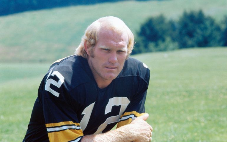 (Original Caption) USA: Terry Bradshaw, #13 football player for the Pittsburgh Steelers. He is wearing a black and yellow uniform crouched down on the grass.
