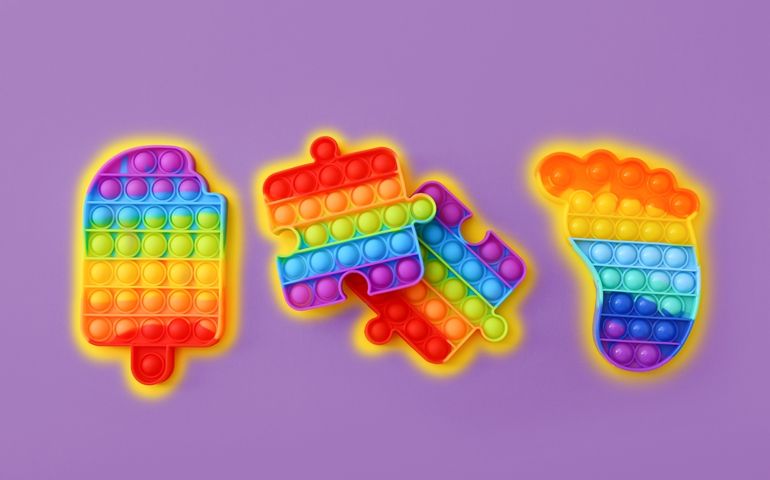 Colorful Push Pop It Bubble Sensory Fidget Toys of different shapes on purple background