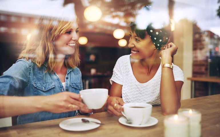 Two multi ethnic friends enjoying coffee together
