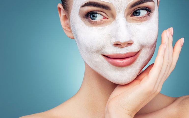 Happy young girl with facial mask on her face