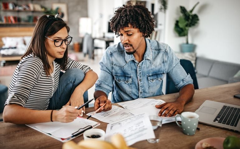 Modern married multi-ethnic young couple calculating financial bills at home