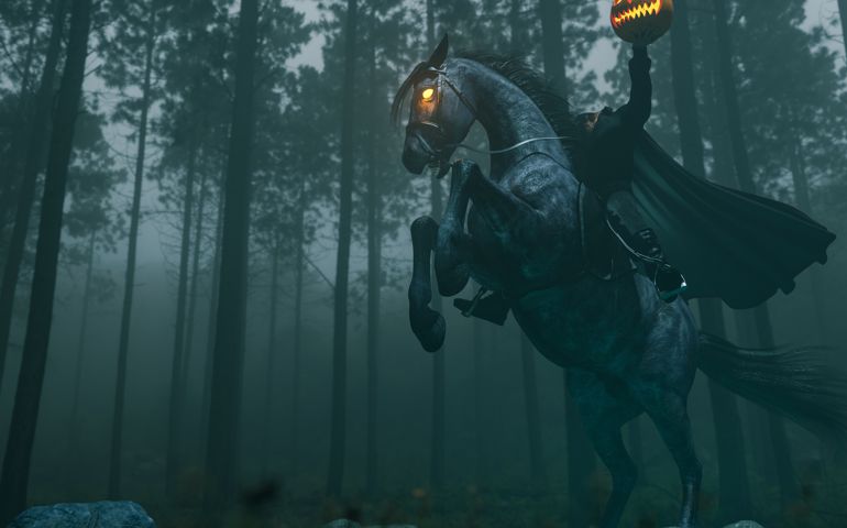 The headless horseman is shown on the back of a rearing demonic horse with glowing eyes. He holds a pumpkin aloft in his left hand.