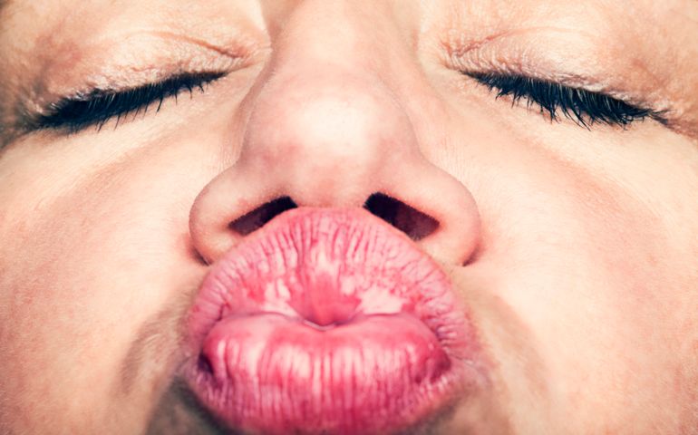 Close-up of woman puckering up her lips for kiss.