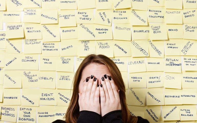 Hands over face, woman hides from excess of business buzzwords
