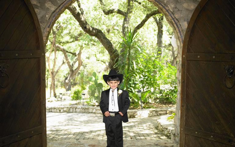 Boy (3-5) wearing tuxedo and cowboy hat, smiling, portrait