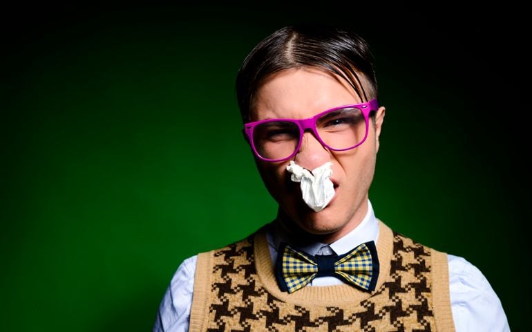 funny sick nerd with tissue in his nose grimacing.