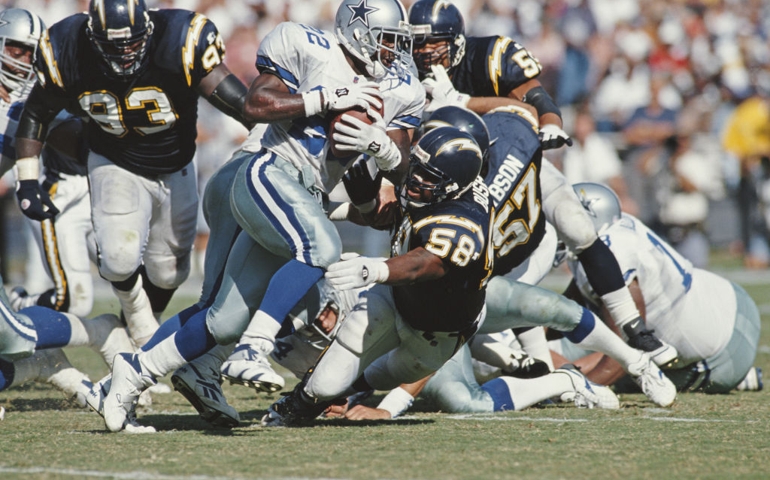 Emmitt Smith #22, Running Back for the Dallas Cowboys runs the ball as Lewis Bush #58 of the San Diego Chargers attempts to tackle him during their American Football Conference West game on 15 October 1995 at the Jack Murphy Stadium, San Diego, California, United States. The Cowboys won the game 23 - 9.