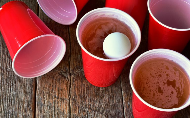 A close up image of red plastic beer pong cups filled with beer.