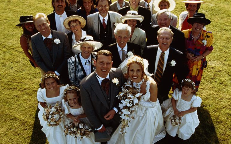 Portrait of bride, groom and family standing on lawn, elevated view