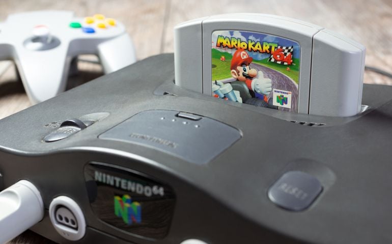 A closeup view of a Nintendo 64 game console, featuring the Mario Kart 64 game cartridge.