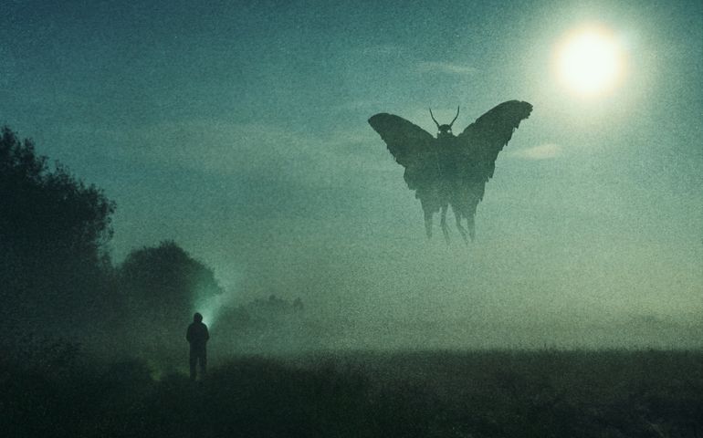 a man looking at a mysterious monster Mothman figure, flying in the sky