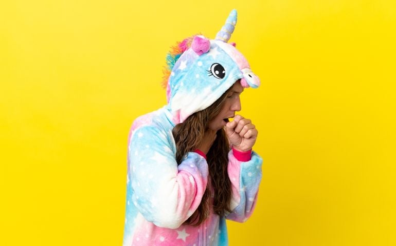 Girl with unicorn pajamas over isolated background is suffering with cough and feeling bad