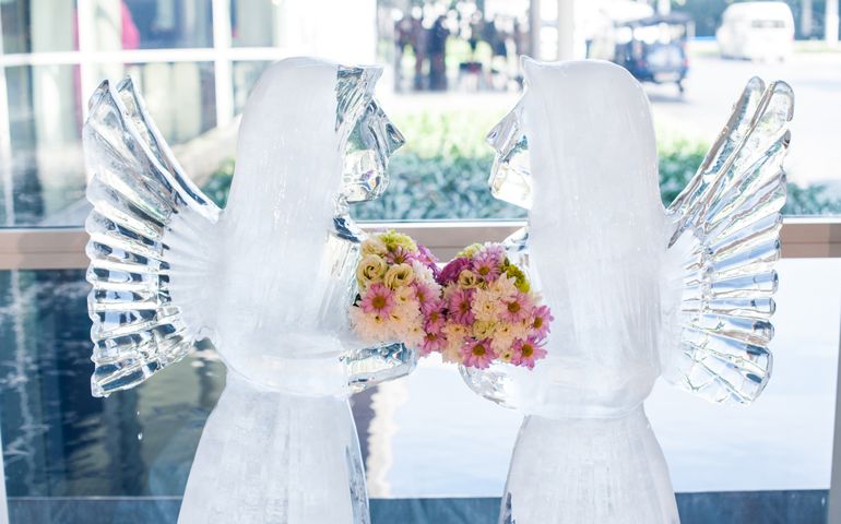 Romantic frame of Ice angel sculpture looking together with beautiful bouquet flower presentation in wedding ceremony