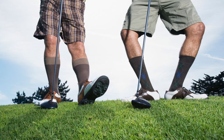 Multi-ethnic men on golf course stretching