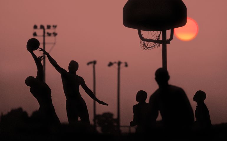 Group of African Americans playing basketball at sunset inat high school basketball court. in Silhouette.