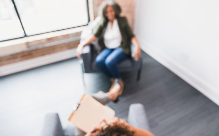 High angle, blurry view of an unrecognizable female therapist offering advice to a mature female client.