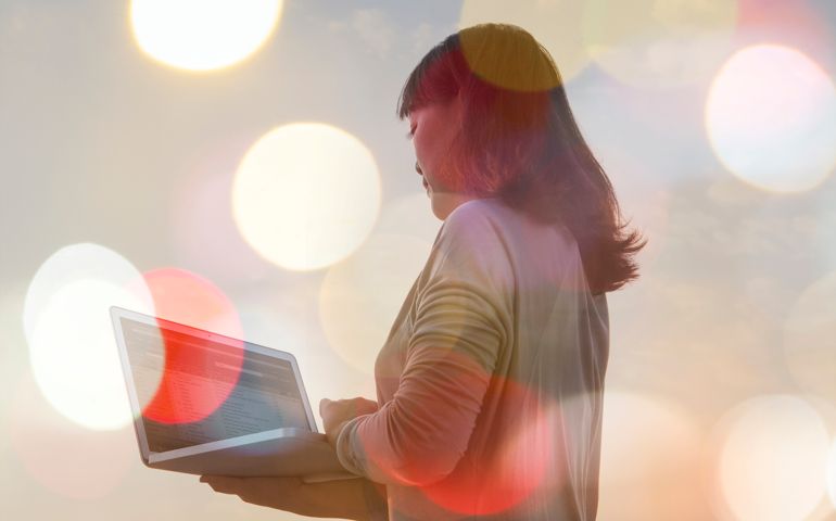 composite of woman using laptop and blurred lights