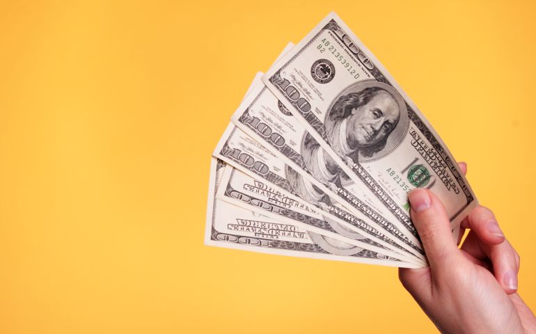 Woman holding 500 dollars against a yellow background.