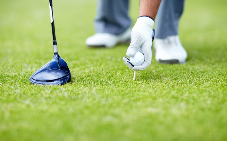 A male golfer placing his golf ball and tee in the ground