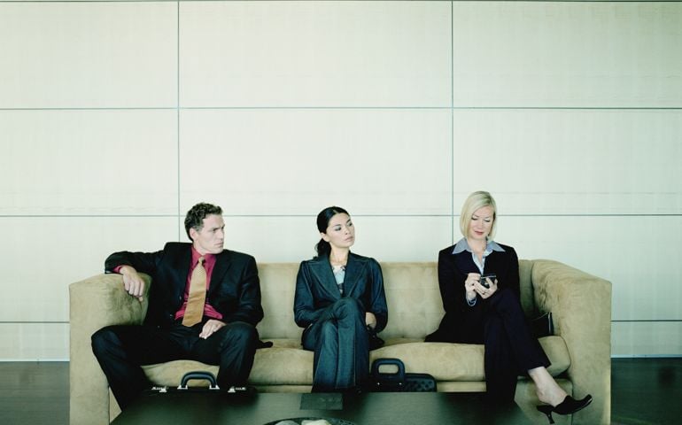 Business people seated on couch watching woman use hand-held computer