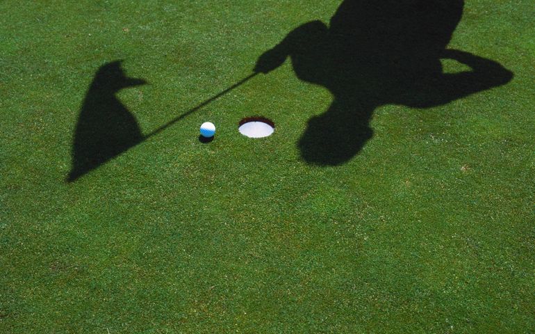SHADOW OF GOLFER &amp; FLAG AT HOLE WITH BALL