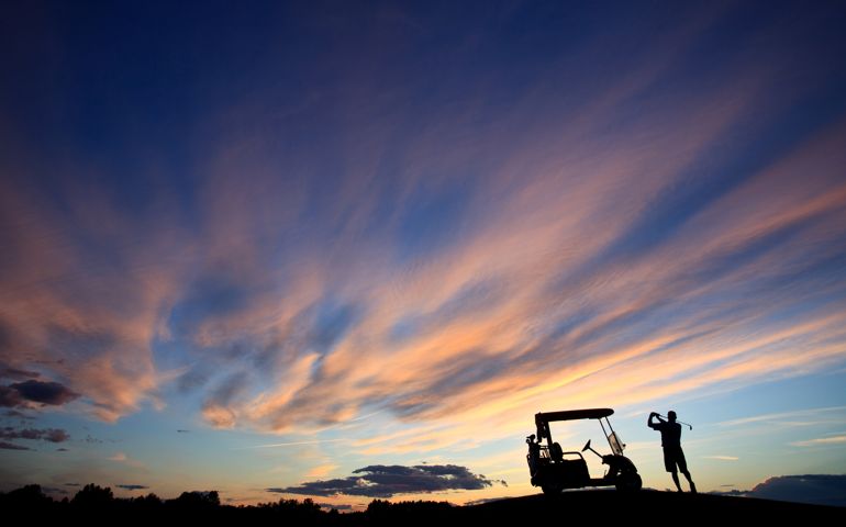 A silhouette of a senior golfer swinging by his golf cart with dramatic sunset sky. Unrecognizable middle aged golfer enjoying the view from the golf course. Resort golf course in the United States. Dramatic sunset sky is unaltered. One of the most spectacular sunsets this photographer has witnessed. Themes include recreation, leisure, guys golf, mens golf, country club, senior golf, retirement, leisure, active lifestyle, healthy living, golf, and sports. There is plenty of copyspace in the image as a wide angle lens was utilized for this shot. Self timer and self portrat.