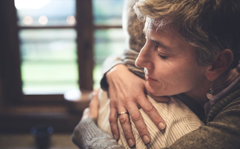Senior couple embrace themselves in their kitchen