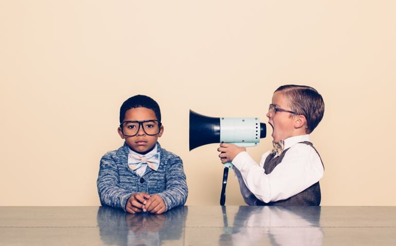 A young boy nerd shouts at the top of his voice to his co-worker through a megaphone trying to talk some sense into him but he is not listening and is ignoring him. The young nerds are dressed in bowties and glasses. Retro styling.