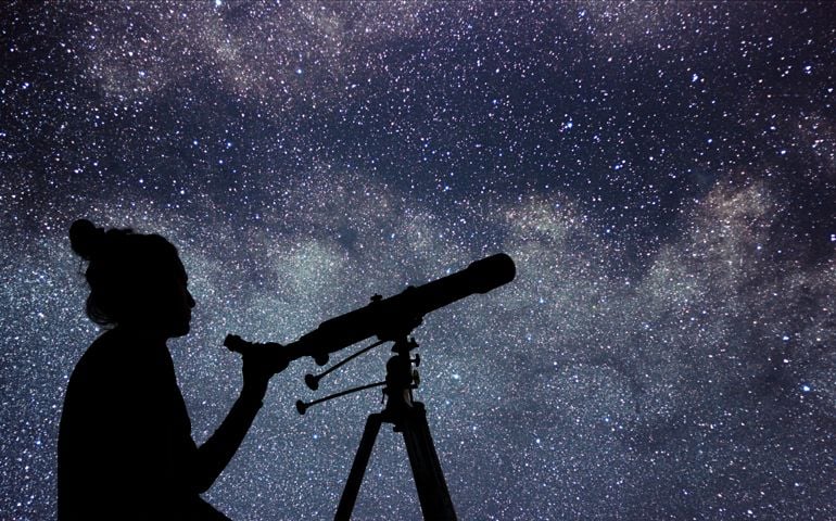 Woman with telescope watching the stars. Stargazing woman and night sky.