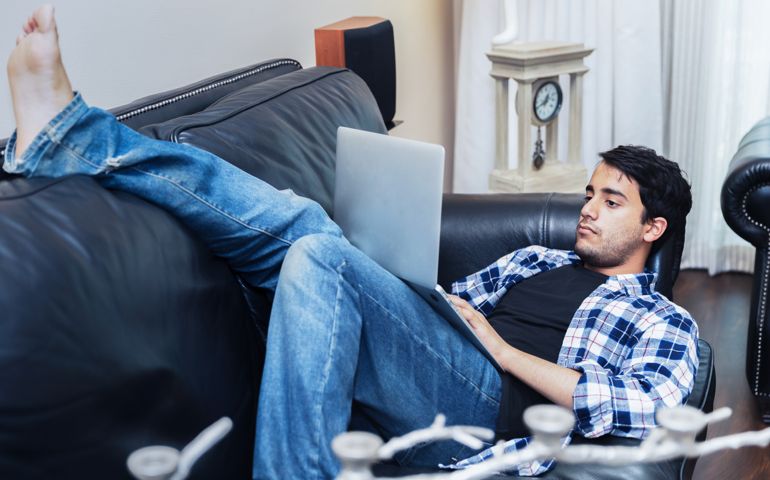 Teenage boy relaxing and using his device to explore his social media account.
