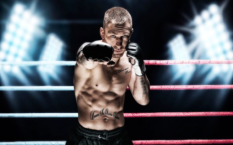 Mixed martial artist posing in the ring against spotlights