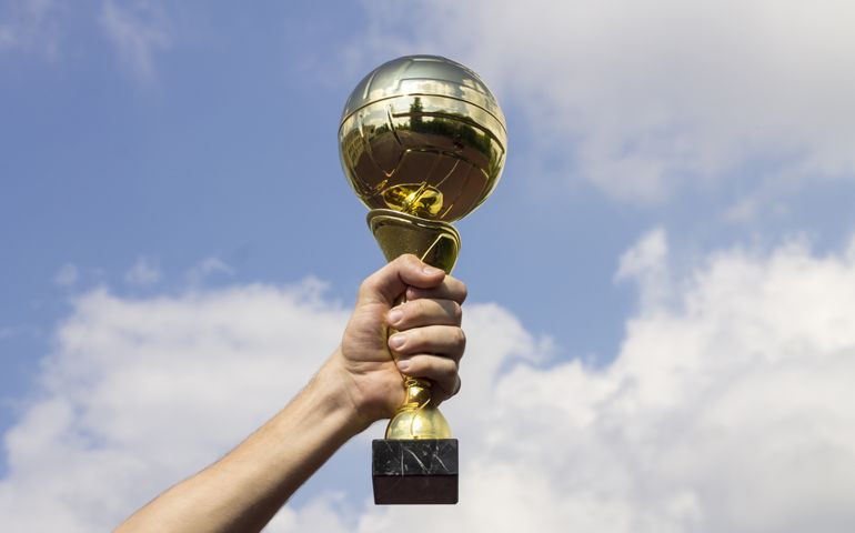 man holding a golden cup against the sky