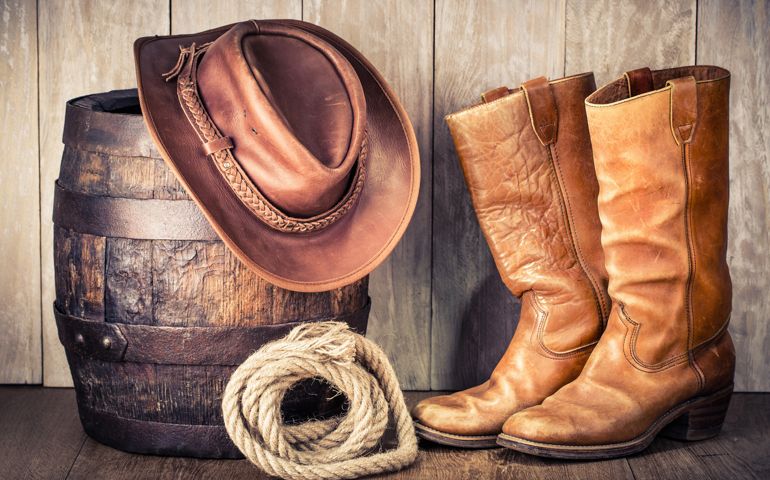 Wild West retro leather cowboy hat, old boots and oak barrel. Vintage style filtered photo