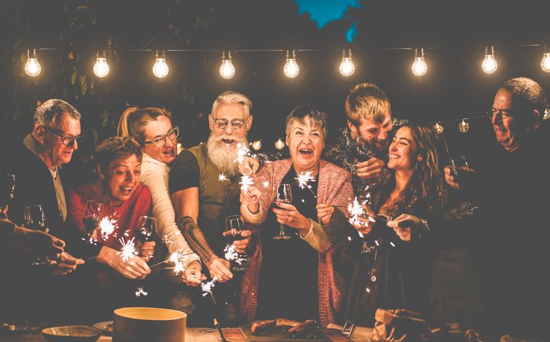 Happy family and friends celebrating with sparkler fireworks after dinner - Different age of people having fun drinking wine at birthday bbq party outdoor - Celebration concept - Focus on center faces