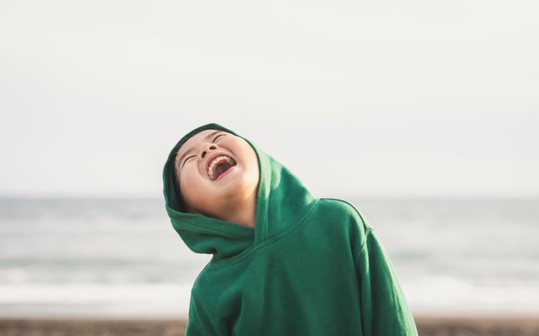 Asian boy wearing hoodie playing in the beach.