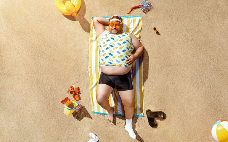 High angle view of funny overweight tourist resting on the beach with copy space