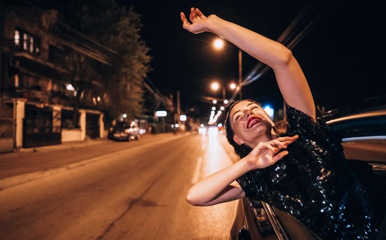 Beautiful girl got out through the open window in the cab and laughing during ride.