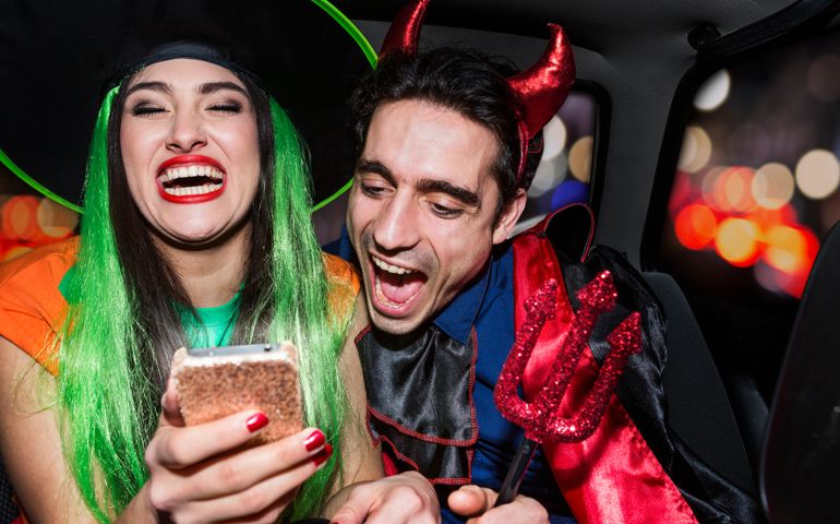 Halloween witch and devil laughing in back of car
