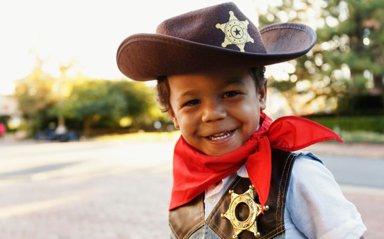 Mixed race boy in cowboy costume smiling outdoors