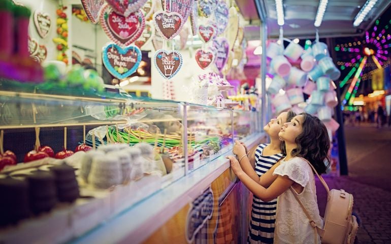 Two little girls are looking sweets in the candy wagon at the fun fair